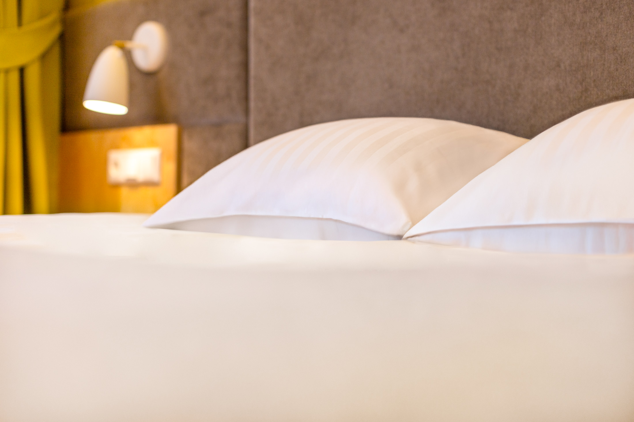Hotell Tartu hotellitoa valged padjad ja voodipeats lugemislambiga - mugav hotellivooodi Tartus
