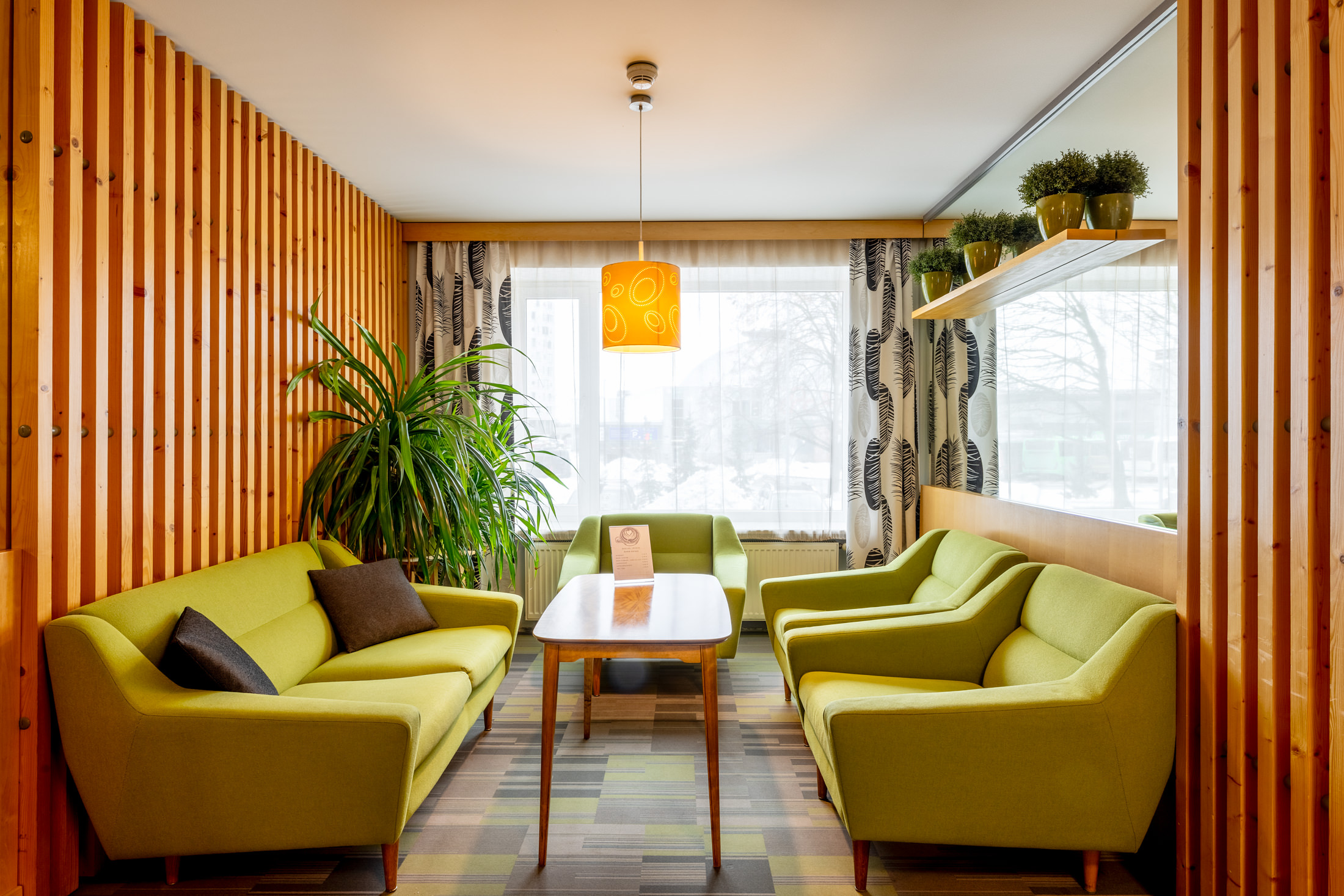 Hotell Tartu lobby istumisala roheliste diivanite ja puitribiseintega - hubane puhkeala Tartu hotellis